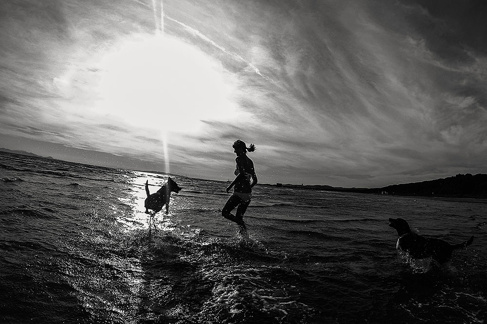 beach wedding in tuscany, bride playing in water with their dogs